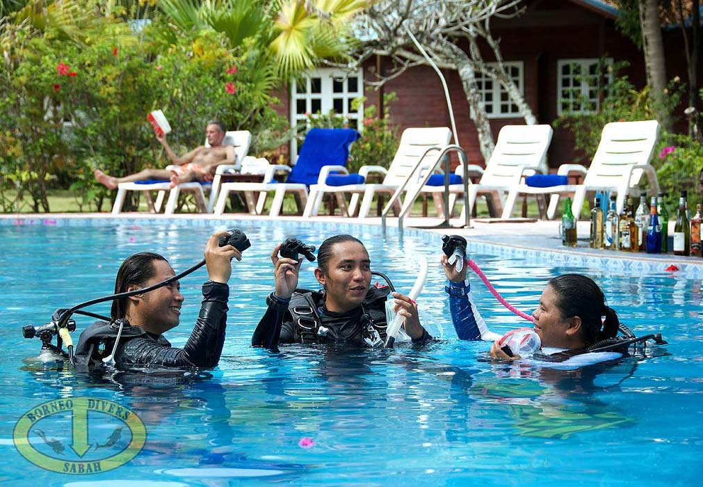 PADI dive instructor teaching a student essential scuba skills in the shallow, clear waters of a tropical island.