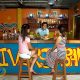 The cozy, rustic interior of the Borneo Divers Bar at a tropical resort, with wooden furniture and warm lighting perfect for post-dive stories.