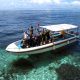 Happy group of divers in full scuba gear waving from a dive boat, ready for an exciting day of diving at Sipadan with Mabul Water Bungalows.