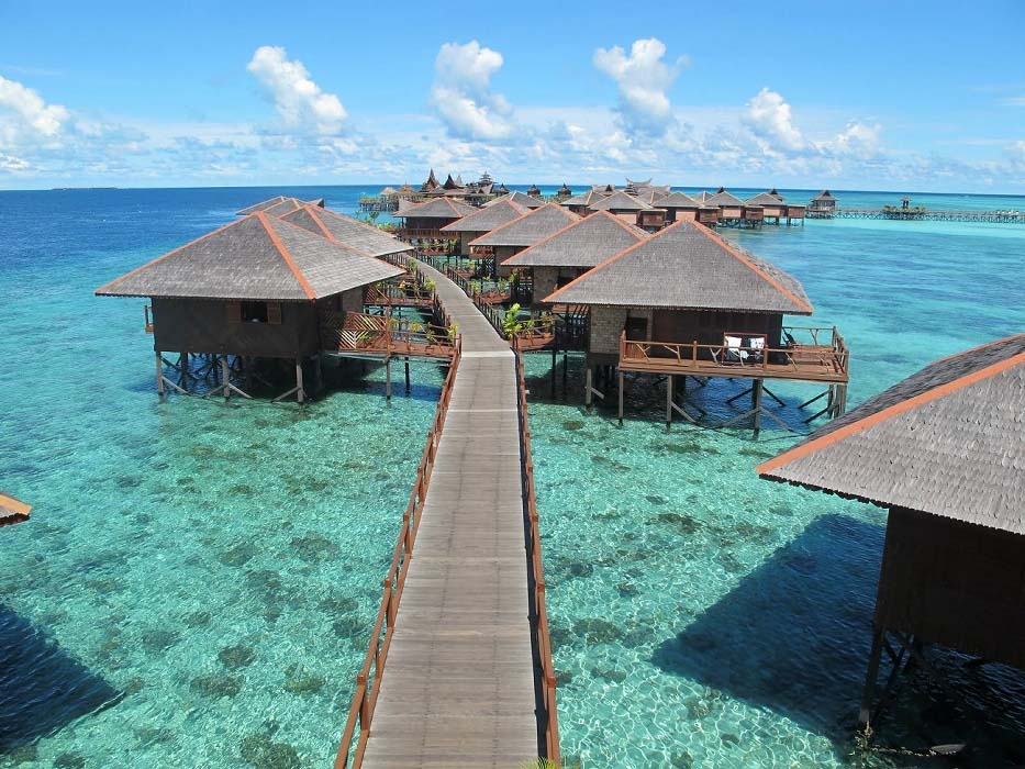 Breathtaking aerial view of the iconic Sipadan Water Village resort, with its overwater bungalows forming a flower shape over a turquoise lagoon.
