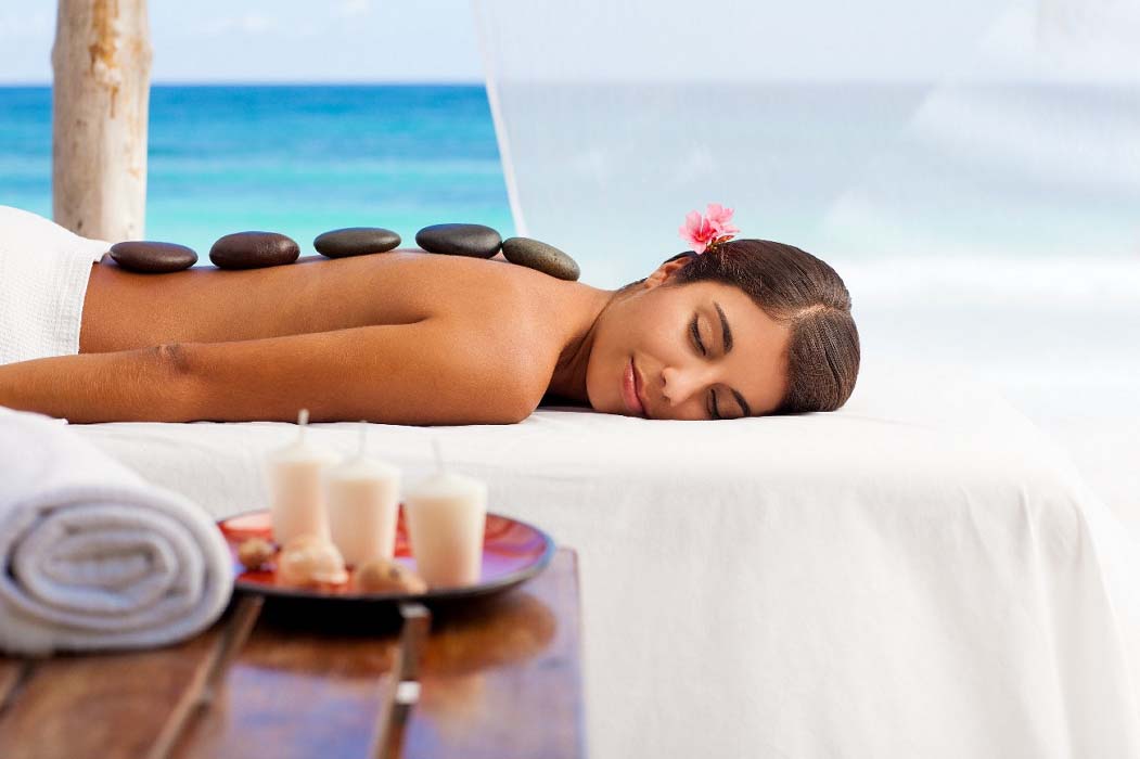 Guest receiving a relaxing hot stone massage treatment at the Mabul luxury resort & spa, a perfect way to unwind and de-stress on holiday.