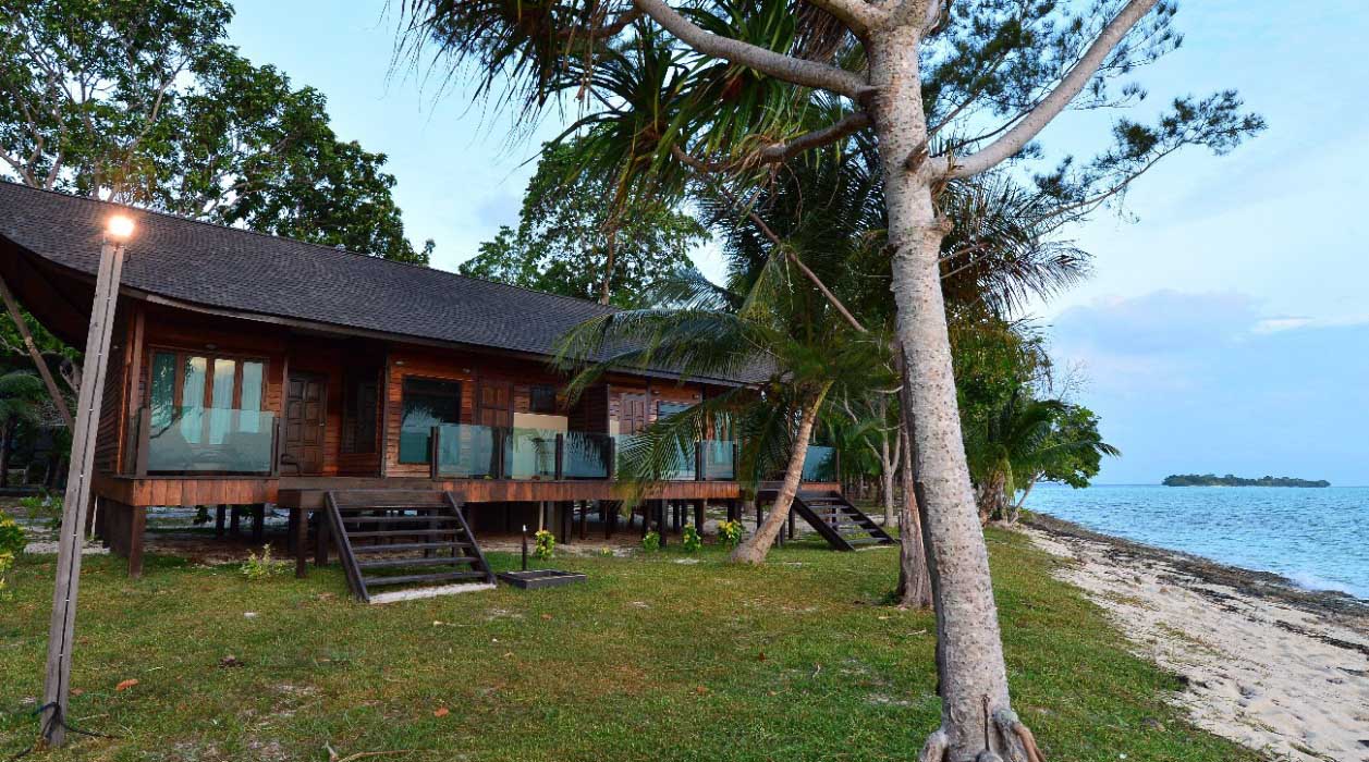 Beachfront view of a luxury wooden chalet at Mataking Island Resort, perfectly situated on the sand with the sea just steps away.