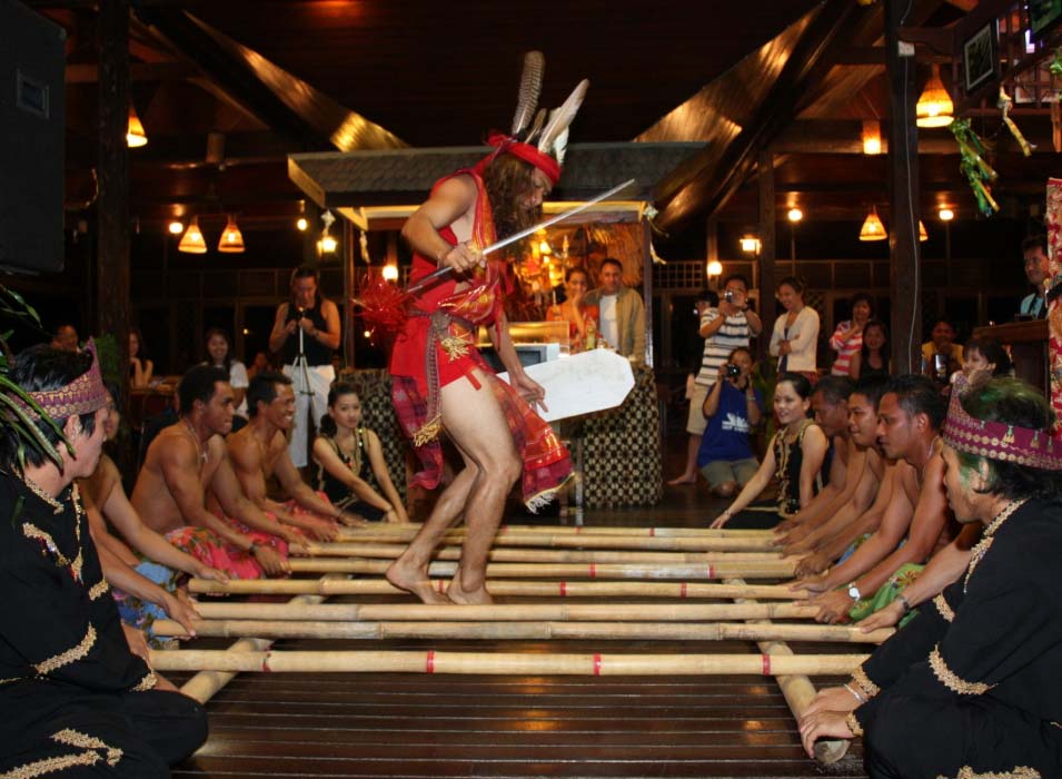 Performers in traditional attire showcasing the exciting Magunatip bamboo dance for guests at a Mabul resort.