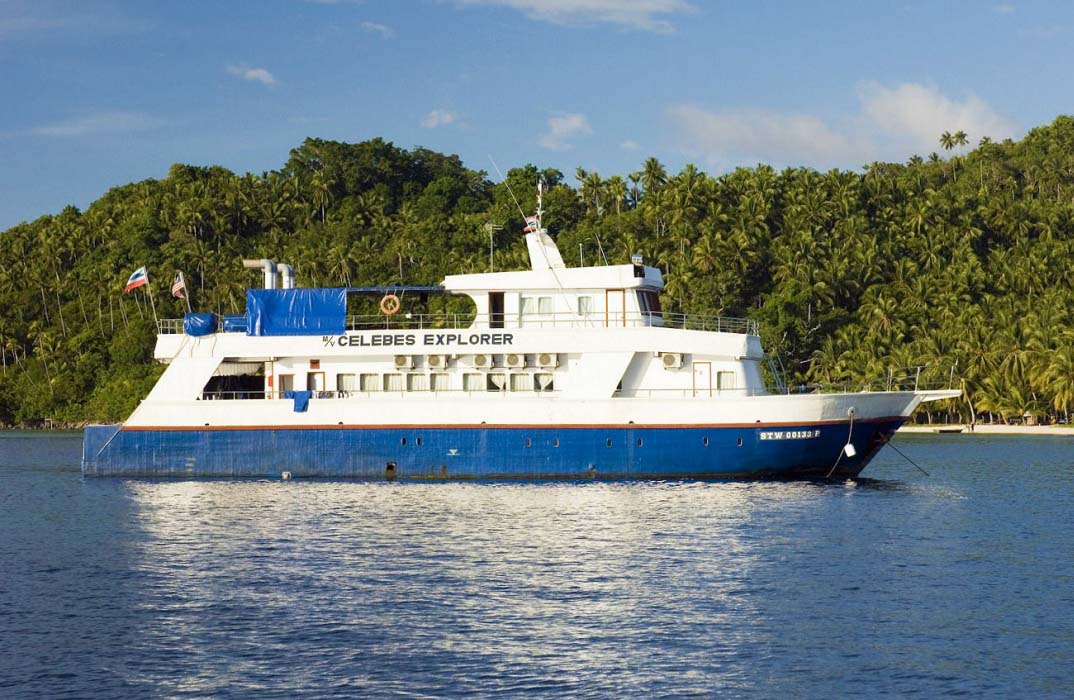 The MV Celebes Explorer liveaboard ship anchored in the calm, blue waters off Mabul Island, ready for a Sipadan diving expedition.