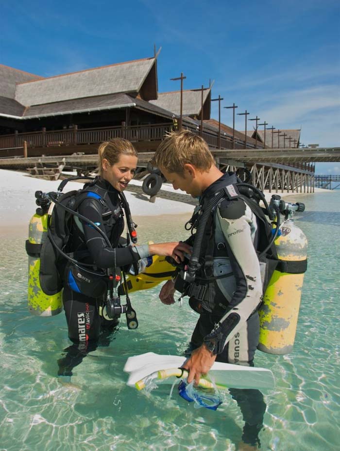 PADI dive instructor teaching a student essential scuba skills in the shallow, clear waters of Mabul island.