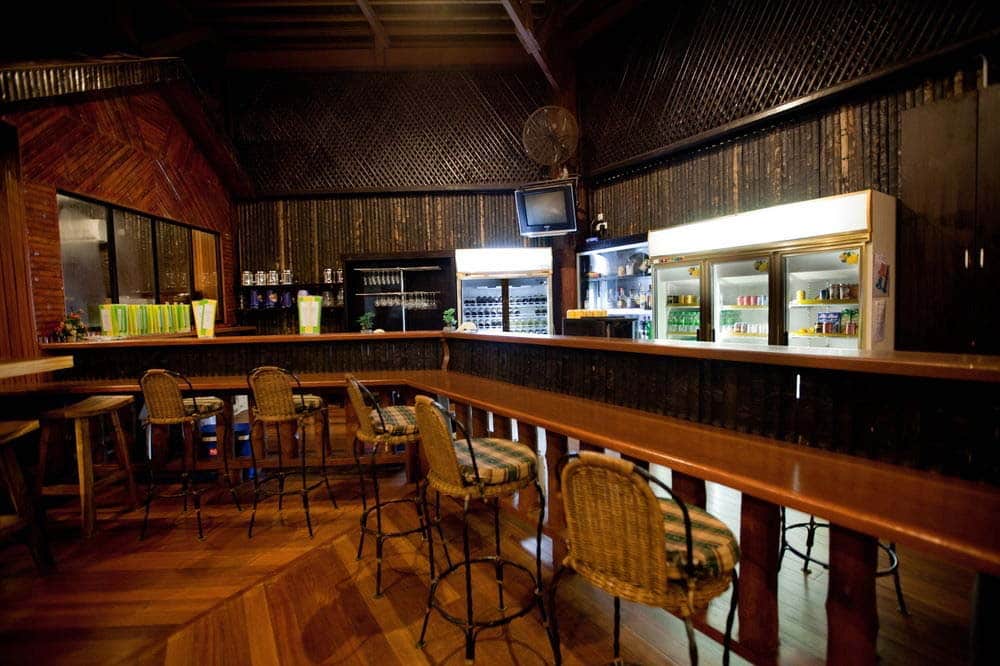 A Mabul island beach bar with a thatched roof and wooden stools, the perfect spot to enjoy a drink after a long day scuba diving.