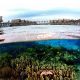 A stunning split shot showing the overwater chalets of Kapalai Resort and the vibrant coral reef below the surface.