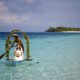 Couple enjoying a traditional wedding ceremony on a floating raft in the turquoise shallows of Mataking Island, a perfect luxury honeymoon destination.