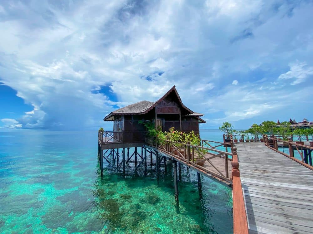 Exterior view of a beautiful overwater chalet at Sipadan Water Village, showcasing its traditional architecture and private balcony.