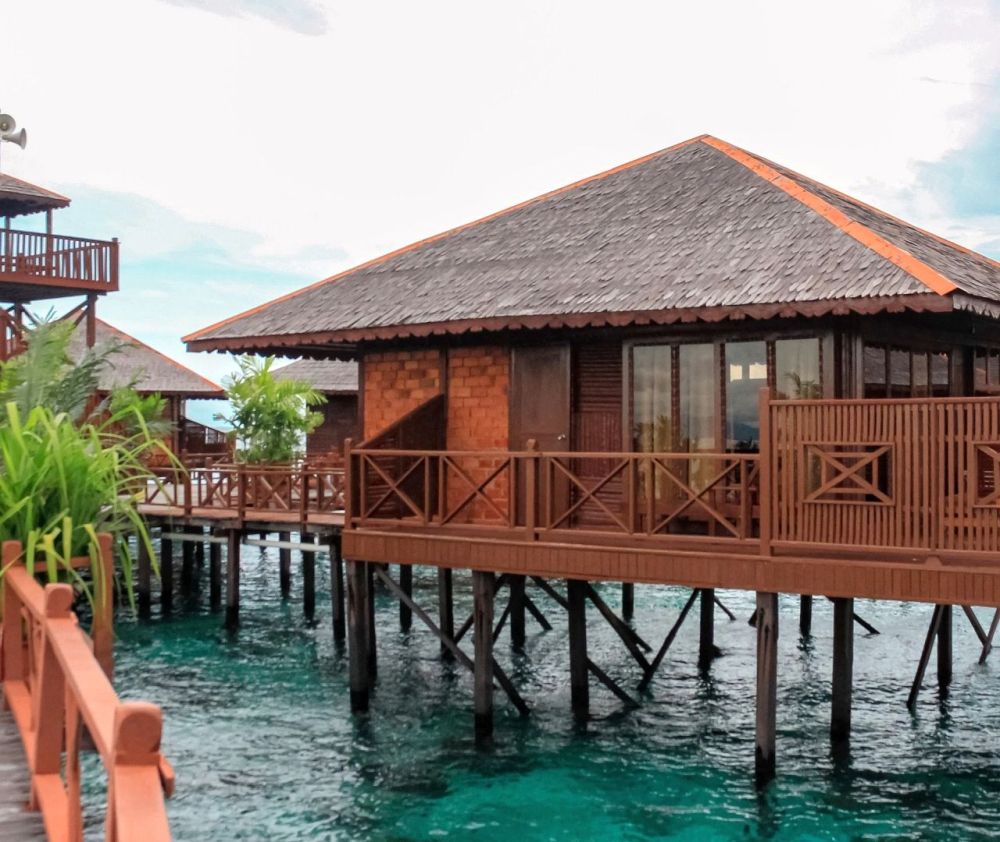Exterior view of a beautiful overwater chalet at Sipadan Water Village, showcasing its traditional architecture and private balcony.