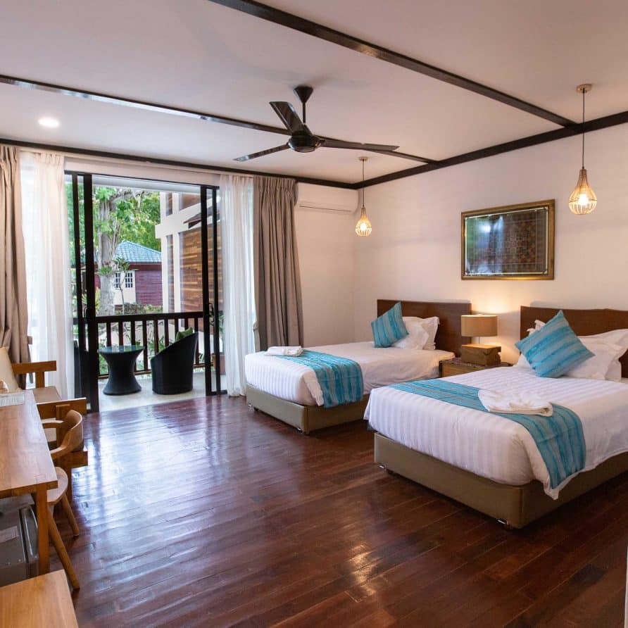 Spacious and stylish Villa Twin Room at Borneo Divers Mabul Resort, with polished wood floors and a private balcony overlooking the tropical gardens.