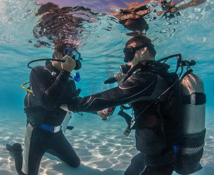 Beginner diver taking their first breaths underwater during a PADI Discover Scuba Diving (DSD) experience in the calm, shallow lagoon of Mabul island.