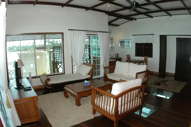 Spacious and elegant living room of the Bougainvilla Suite at Mabul Water Bungalows resort, offering panoramic ocean views along with glass floors for a luxurious stay.