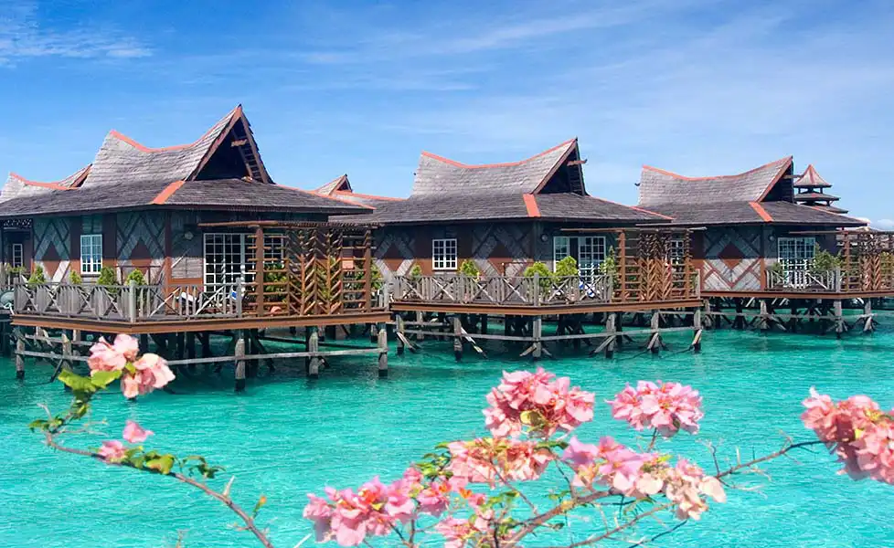 Stunning view of Mabul Water Bungalows resort, showing its iconic overwater chalets aligned over its vibrant turquoise lagoon.