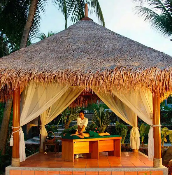Guest receiving a relaxing massage treatment in a tranquil tropical spa setting, perfect for unwinding during a luxury Mabul resort holiday.