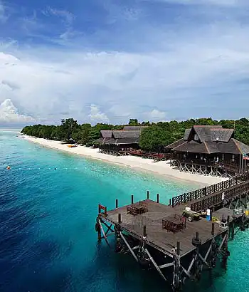 Aerial view of the arrival jetty at Mataking Island Dive Resort, with dive boats moored in turquoise water next to the perfect white sand beach.