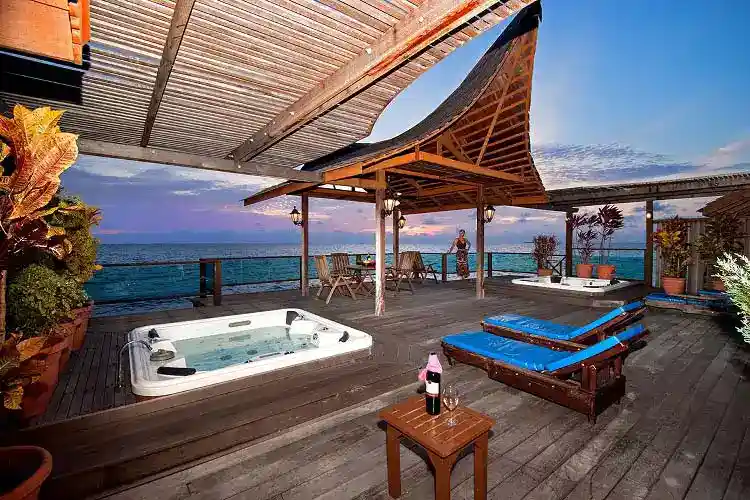 Expansive private sundeck of the Royale Villa at Mabul Water Bungalows, featuring a jacuzzi and lounge chairs for watching the sunset over the sea of Mabul island.