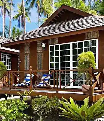 View of Sipadan-Mabul Resort, showcasing the beautiful stand alone beach chalets nestled amongst lush palm trees on a white sand beach.