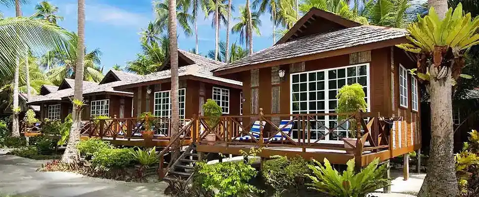 Beautiful wooden chalets at Sipadan-Mabul Resort, nestled amongst lush palm trees and tropical gardens in front of the beach of Mabul island.