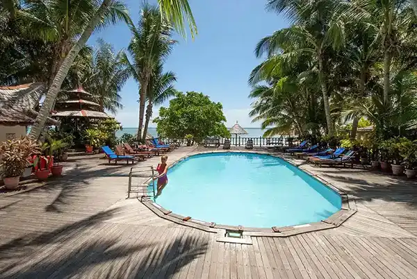 Refreshing swimming pool at Sipadan-Mabul Resort, surrounded by a wooden sundeck and palm trees with a fantastic view of the Celebes sea.