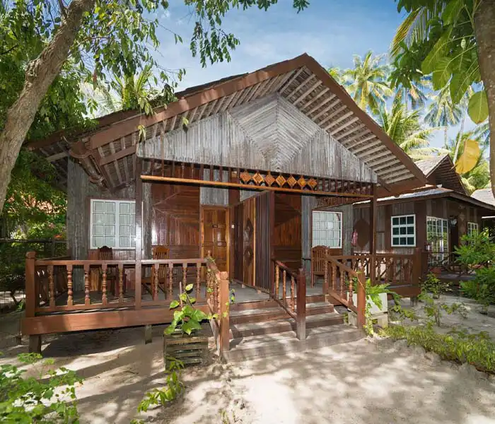 Comfortable interior of a standard chalet at Sipadan-Mabul Resort, featuring twin or double beds, classic wicker furniture, and polished hardwood floors.