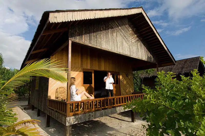 Luxurious beachfront villas with traditional architecture nestled amongst coconut palm trees on a pristine white sand beach at Pom Pom island resort.
