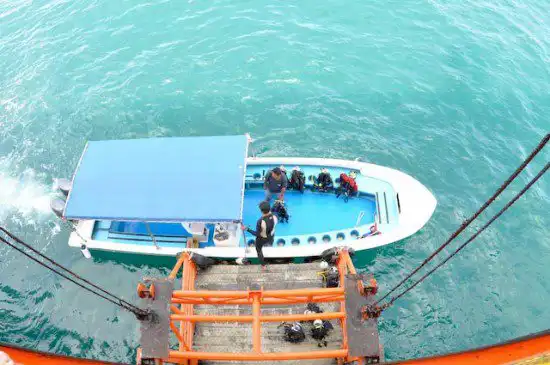 Scuba divers riding the unique platform lift at Seaventures Dive Rig, being lowered directly from the rig into the water for their next dive.